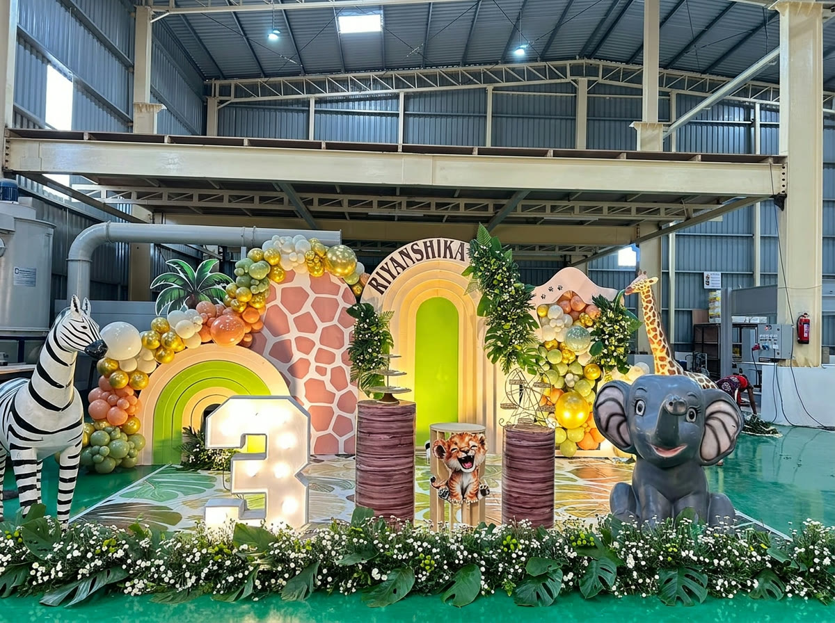 Jungle themed birthday stage with animal props and balloon arch